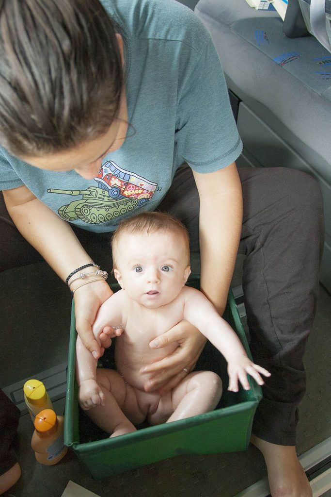 Bañando a un bebé en el barreño plegable de la furgoneta