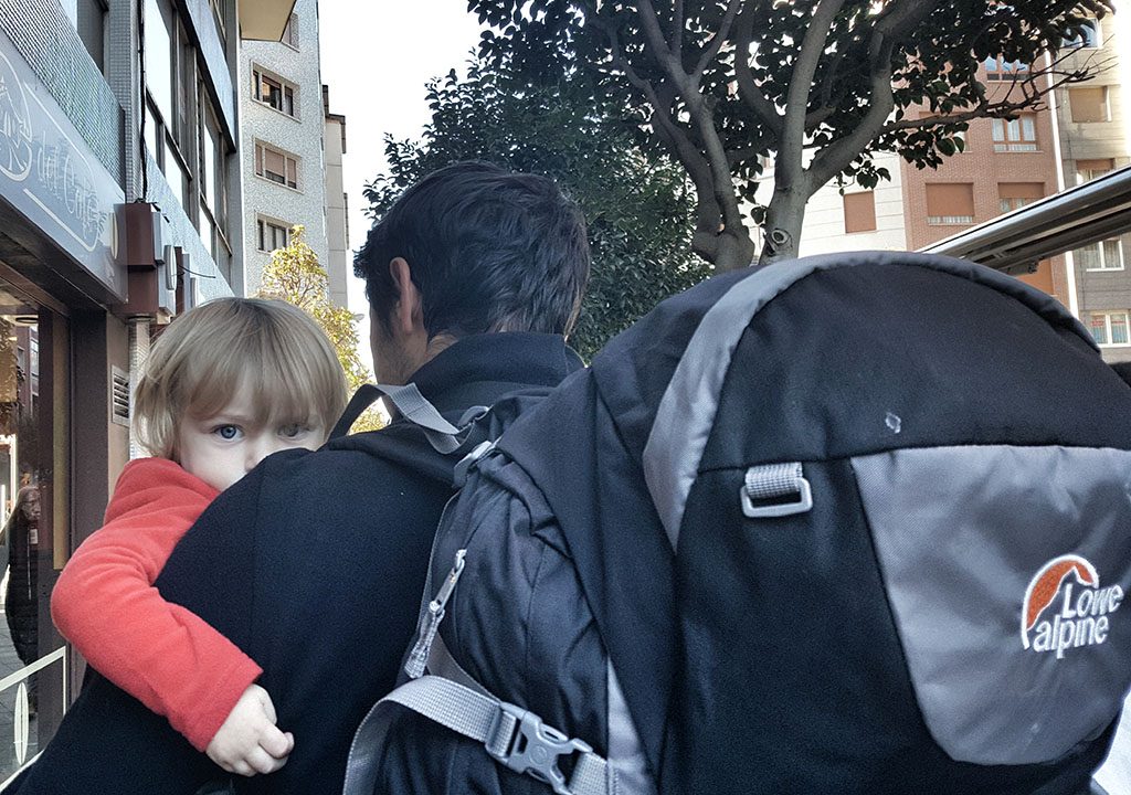 Hombre con mochila llevando a un bebé Hombre con mochila llevando a un bebé