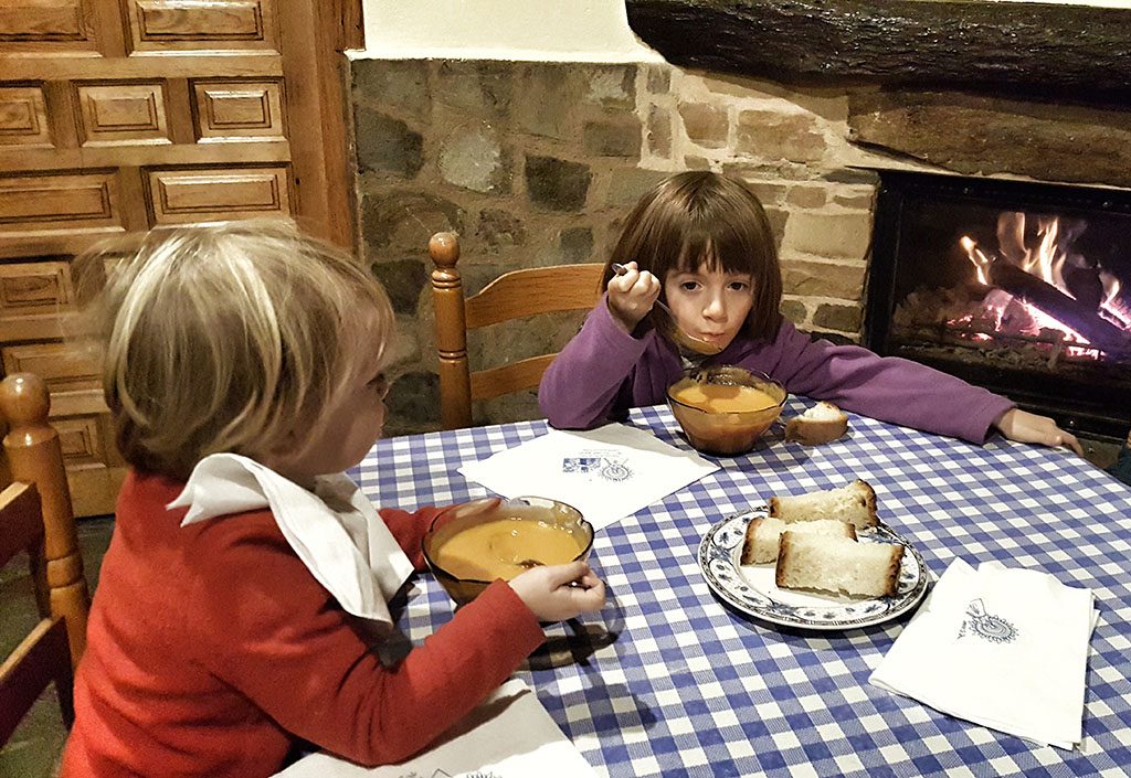 Niñas comiendo puré junto a una chimenea Niñas comiendo puré junto a una chimenea